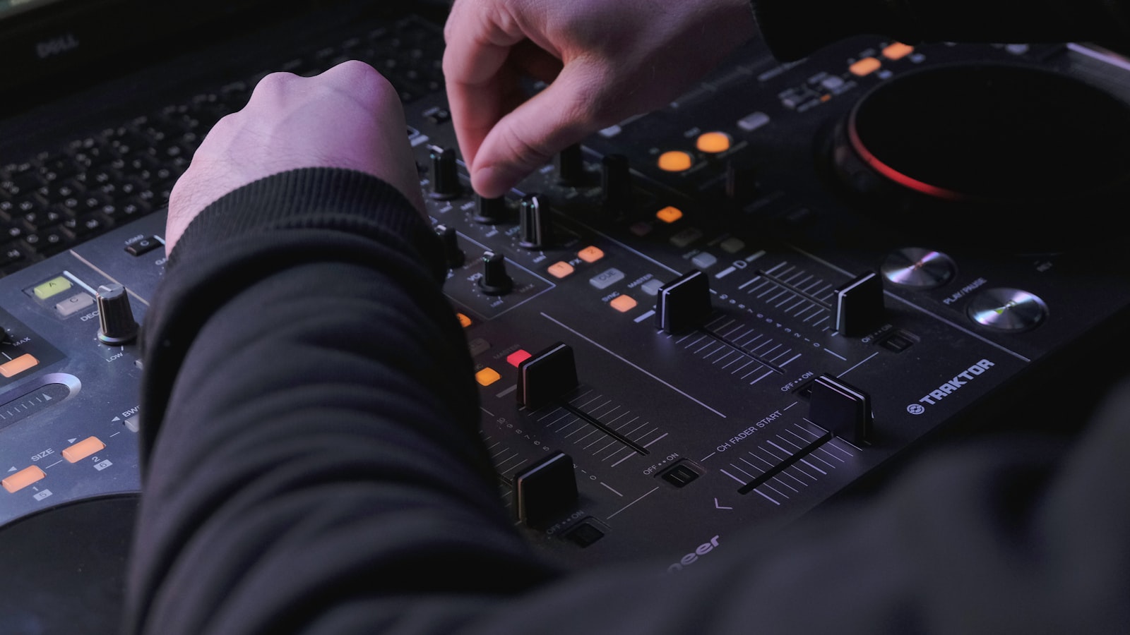 DJ mixer mid-set, hands on crossfader, two turntables/records playing