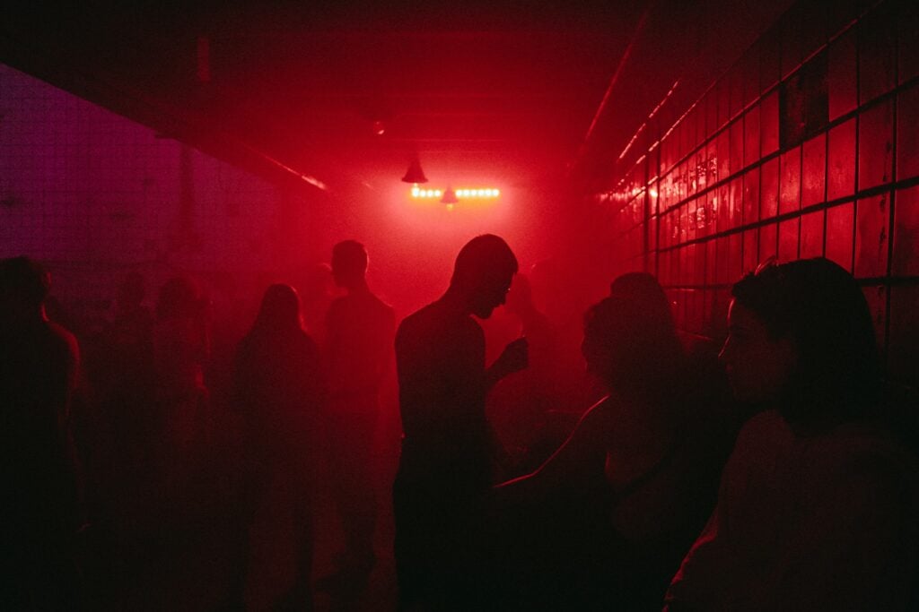 Crowd at a rave with hands raised under stage lights