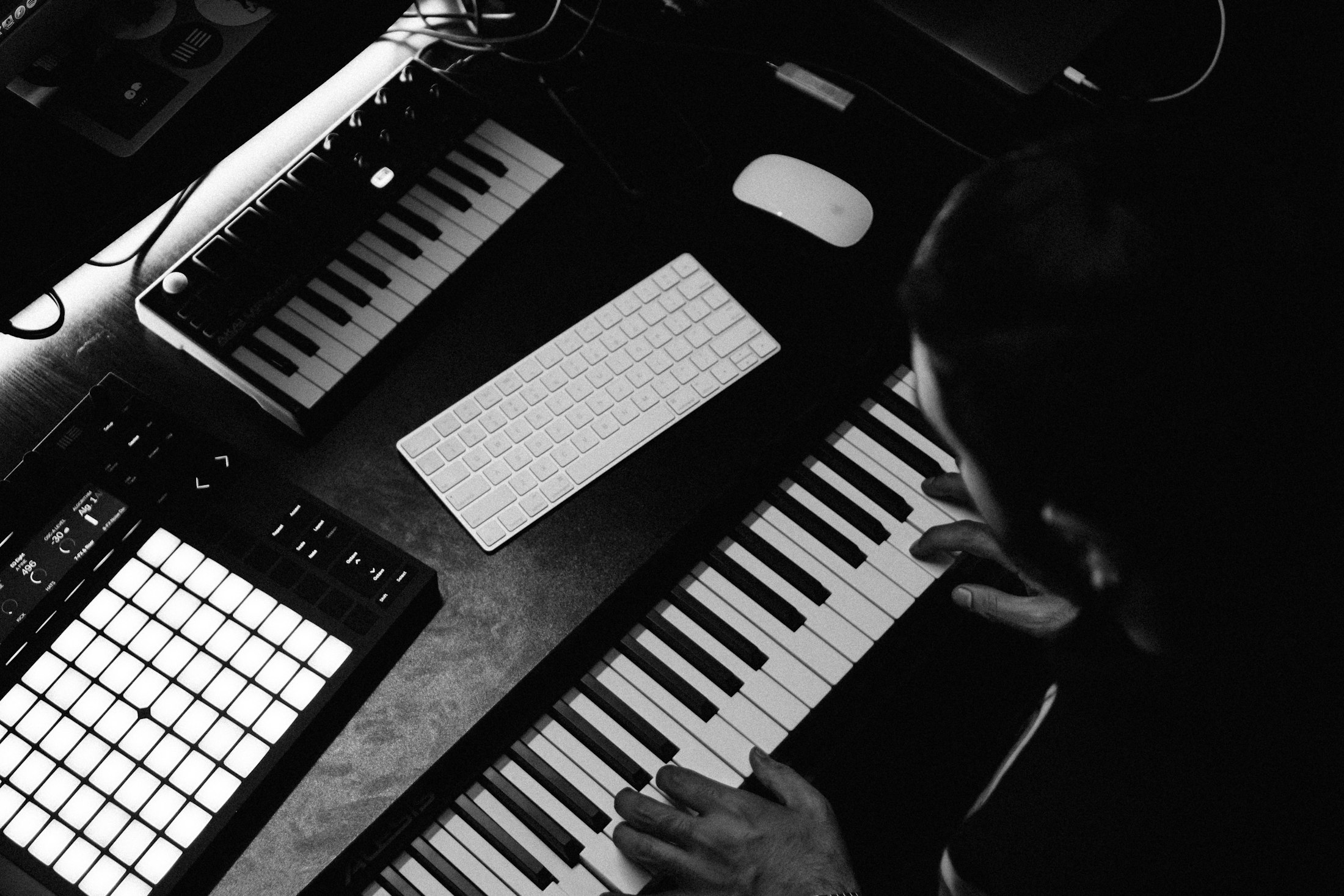 Black-and-white photograph of hands playing a synthesizer keyboard